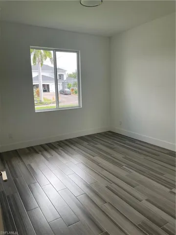 Unfurnished room with wood finish floors and baseboards