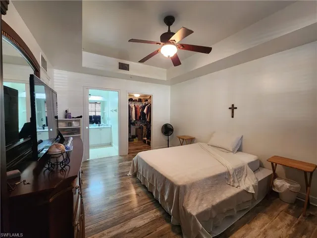 Bedroom with a spacious closet, dark hardwood / wood-style floors, a closet, and ceiling fan