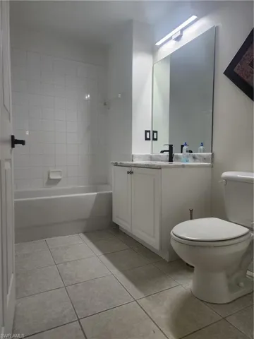 Full bathroom featuring tile floors, tiled shower / bath, vanity, and toilet