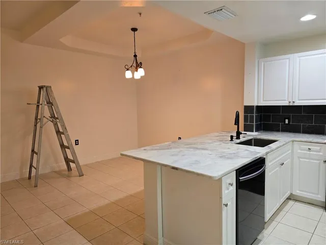 Kitchen featuring black dishwasher, tasteful backsplash, kitchen peninsula, and white cabinets