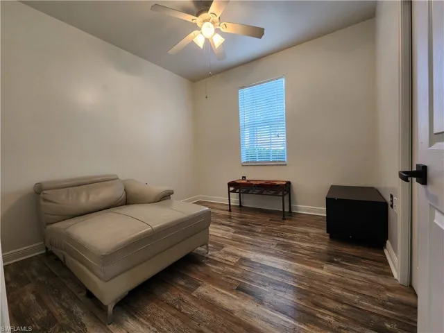 Living area with ceiling fan and dark wood-type flooring