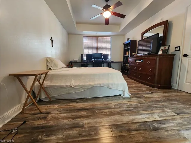 Bedroom featuring ceiling fan, a tray ceiling, and hardwood / wood-style flooring