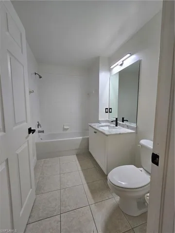 Full bathroom featuring tiled shower / bath, vanity, toilet, and tile patterned floors