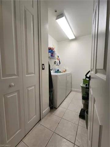 Clothes washing area featuring washer and clothes dryer and light tile flooring