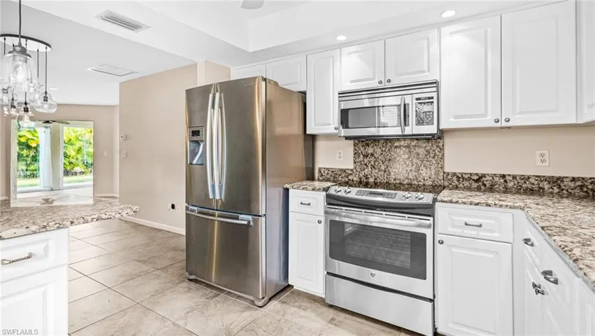 Kitchen featuring beautiful stainless appliances, white cabinets, granite and recessed lighting.