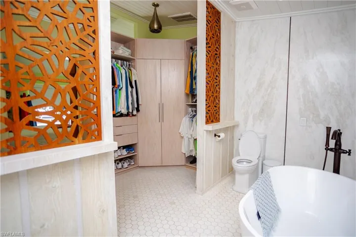 Bathroom featuring a freestanding tub, toilet, and a spacious closet