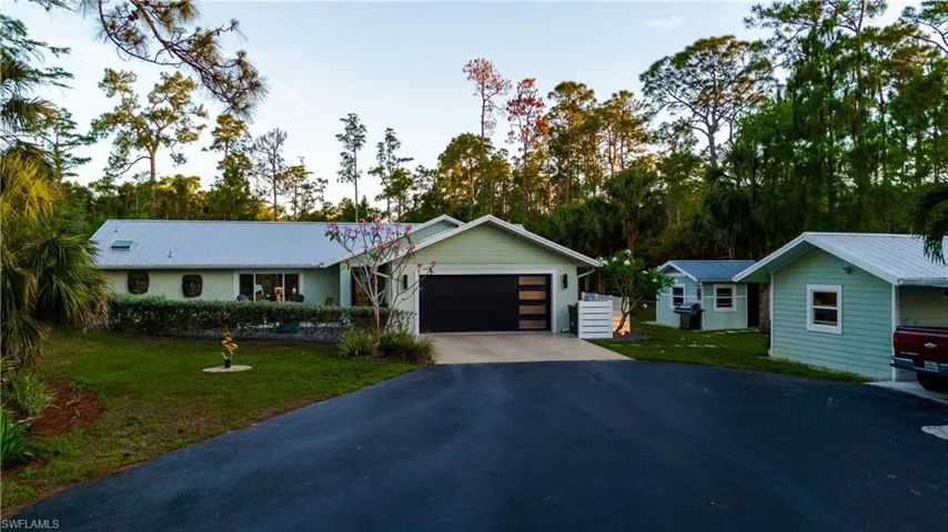 Ranch-style home with asphalt driveway, an attached garage, a front yard, and metal roof
