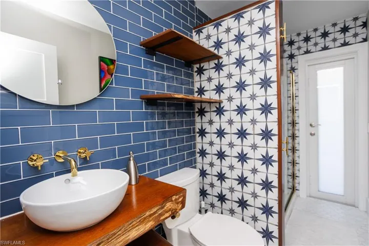 Bathroom with a sink, toilet, tile walls, a shower, and tile patterned floors