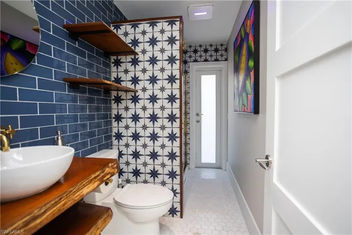 Bathroom featuring tile walls, tile patterned flooring, toilet, baseboards, and vanity