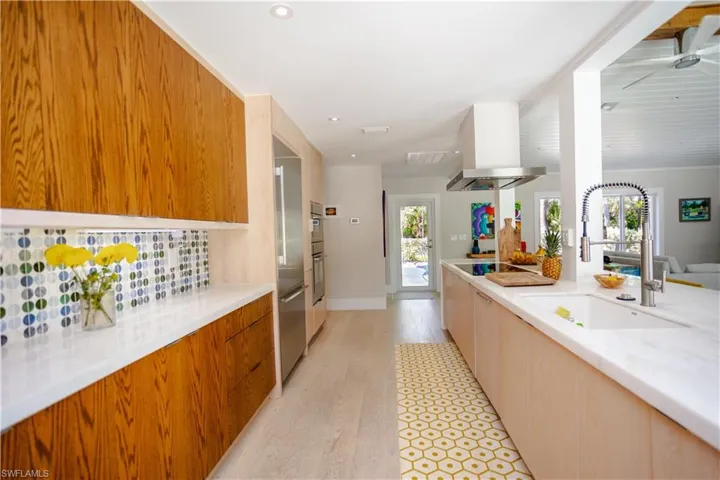 Kitchen featuring modern cabinets, a sink, light wood-style flooring, island exhaust hood, and recessed lighting