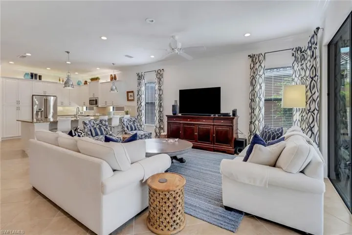 Living room with ceiling fan, light tile patterned flooring, and crown molding