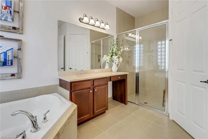 Bathroom featuring tile patterned floors, vanity, and separate shower and tub