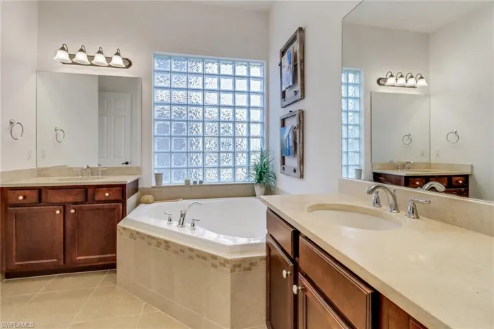 Bathroom with vanity, tile patterned floors, a healthy amount of sunlight, and tiled tub