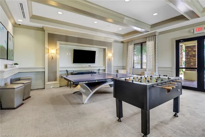 Playroom with light carpet, beam ceiling, a raised ceiling, and ornamental molding