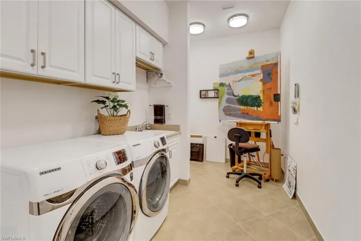 Clothes washing area featuring cabinets, light tile patterned floors, sink, and washing machine and clothes dryer