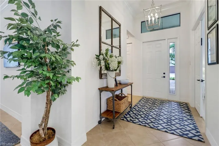Entrance foyer featuring a chandelier, ornamental molding, and light tile patterned flooring