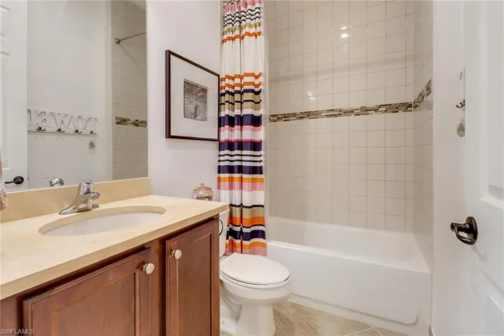 Full bathroom with shower / tub combo, vanity, toilet, and tile patterned floors