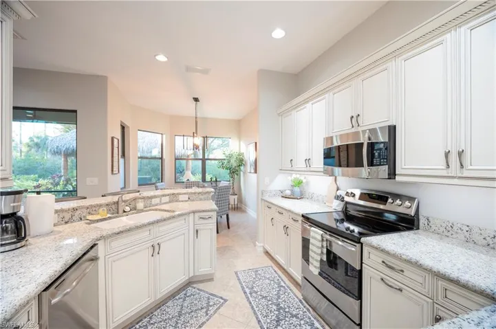 Kitchen featuring stainless steel appliances, light stone counters, healthy amount of natural light, and light tile patterned floors