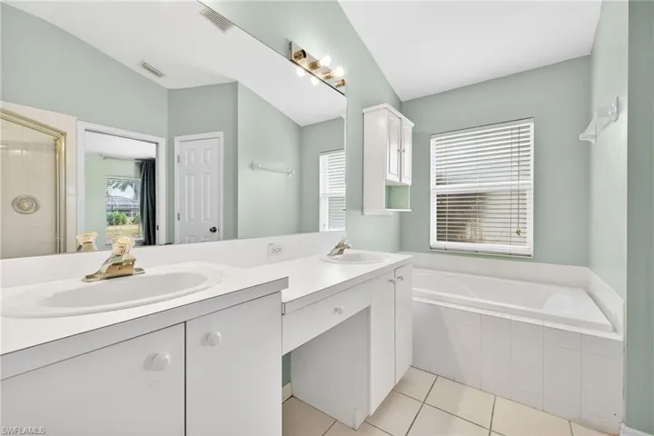 Bathroom with a bath, double vanity, light tile patterned floors, and a stall shower