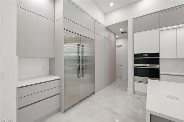 Kitchen with stainless steel appliances, modern cabinets, light marble finish floors, recessed lighting, and gray cabinets