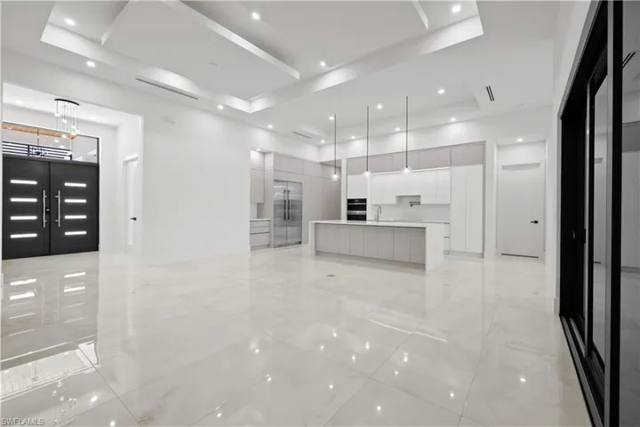 Kitchen with modern cabinets, a tray ceiling, stainless steel built in fridge, and recessed lighting