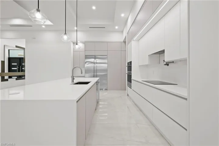Kitchen with modern cabinets, white cabinetry, pendant lighting, stainless steel appliances, and a large island
