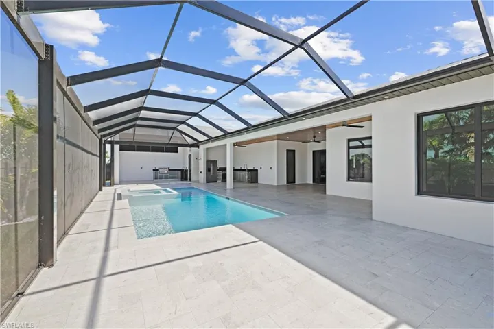 View of pool featuring a sunroom, ceiling fan, glass enclosure, a pool with connected hot tub, and a patio area