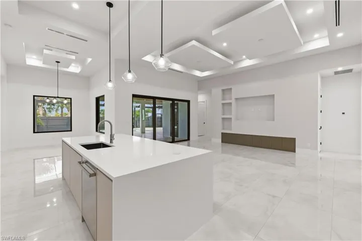 Kitchen with modern cabinets, open floor plan, decorative light fixtures, a kitchen island with sink, and a tray ceiling