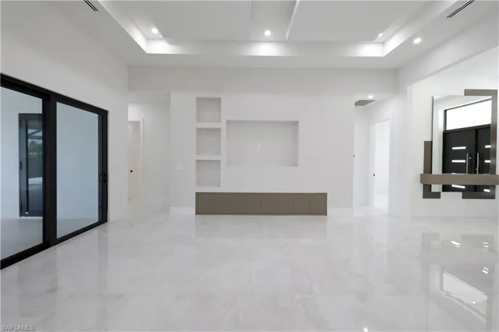 Spare room featuring built in features, a tray ceiling, and recessed lighting