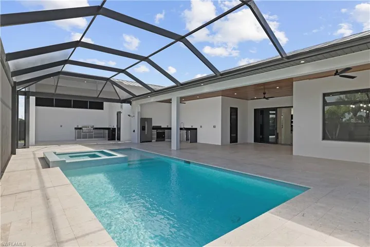 View of pool with exterior kitchen, ceiling fan, a sunroom, and a lanai