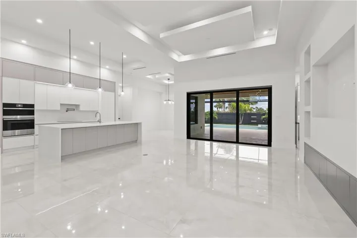Unfurnished living room with a chandelier, light marble finish flooring, built in features, and recessed lighting