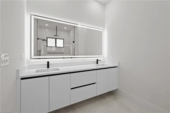Bathroom with double vanity, a shower stall, light tile patterned floors, and recessed lighting