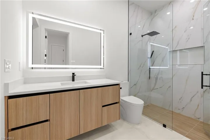 Bathroom with vanity, a marble finish shower, and light tile patterned floors