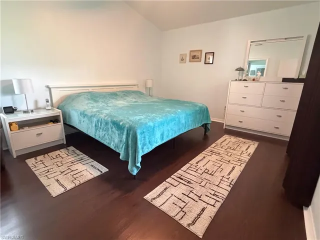 Primary bedroom with beautiful wood floors and vaulted ceiling.