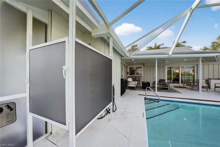 Screened lanai featuring a swimming pool with integrated steps, a covered patio area, and sliding glass doors leading into the residence