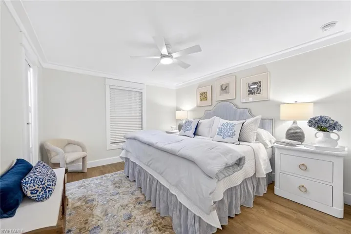 Spacious room featuring wood-finish flooring, a ceiling fan, crown molding, a window with blinds, and painted walls