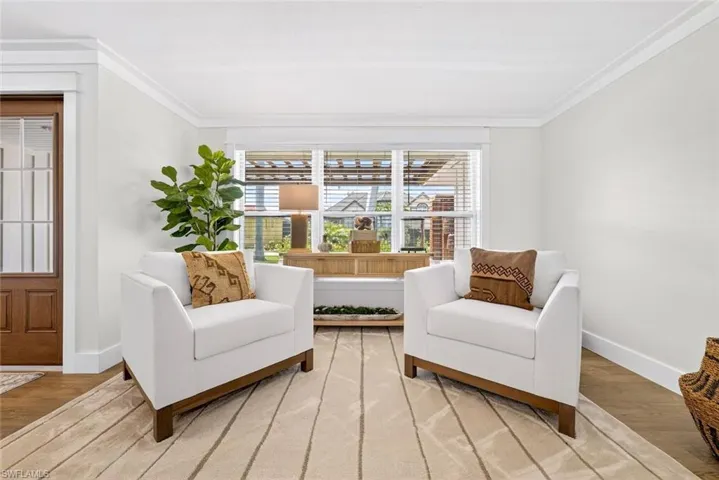 Light-filled room featuring a large window, crown molding, and wood-finish flooring