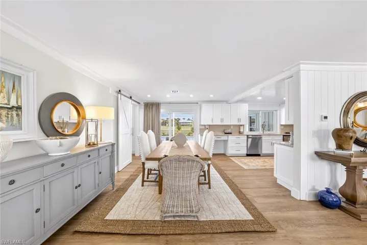 Open-concept dining area featuring wood-finish flooring, a long dining table, and a sliding barn door