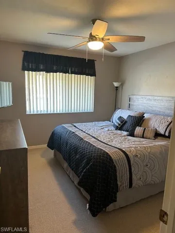 Carpeted bedroom featuring ceiling fan and baseboards
