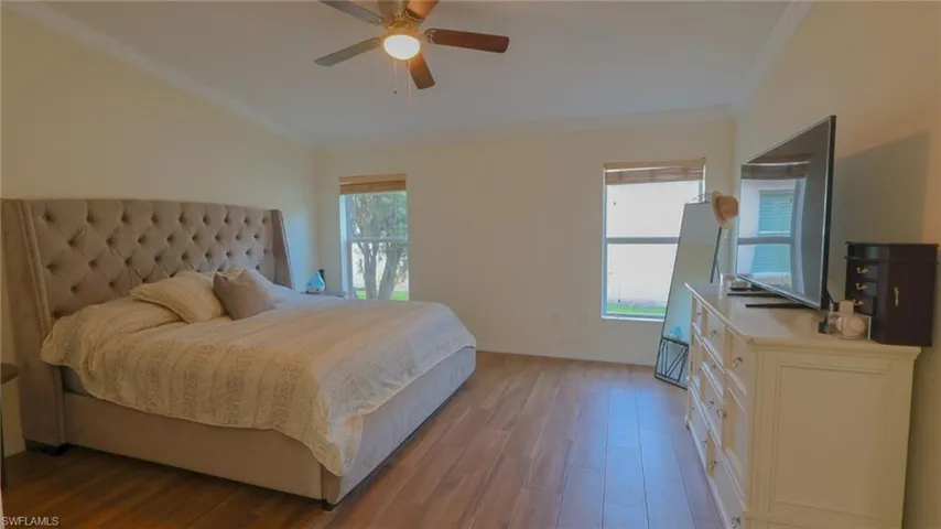 Master Bedroom with baseboards, crown molding, multiple windows, and wood finished floors