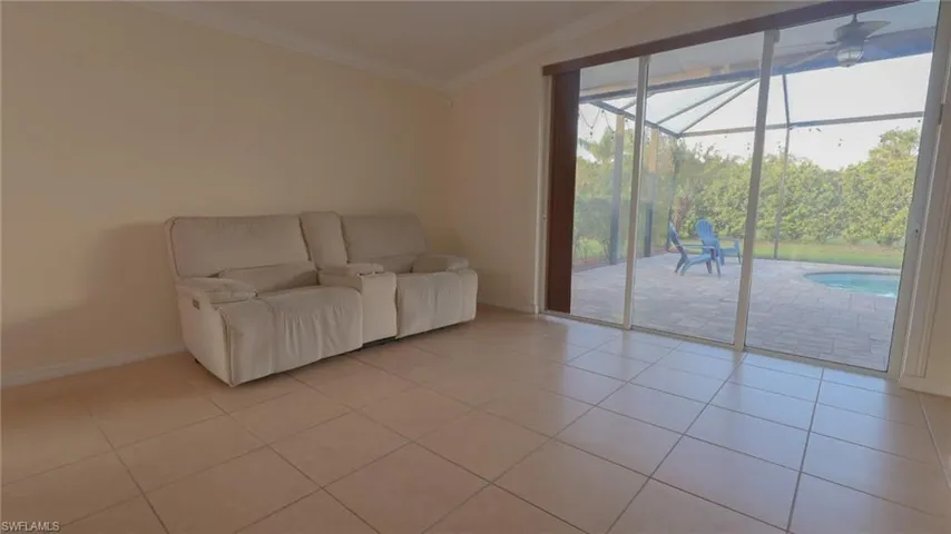 Unfurnished living room with a sunroom, baseboards, ornamental molding, ceiling fan, and light tile patterned floors