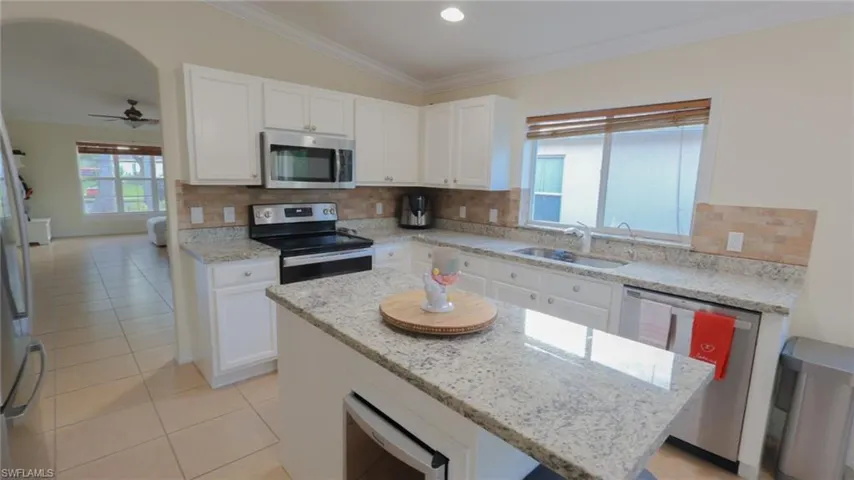 Kitchen with crown molding, a sink, a kitchen island, appliances with stainless steel finishes, and decorative backsplash