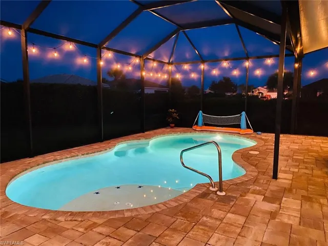 Pool at twilight featuring an outdoor pool, a lanai, and a patio area