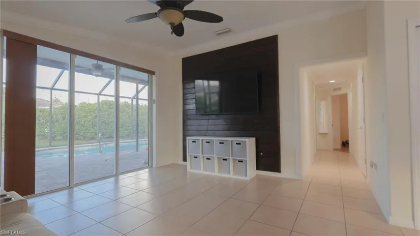 Unfurnished living room featuring light tile patterned floors, ornamental molding, visible vents, and a ceiling fan