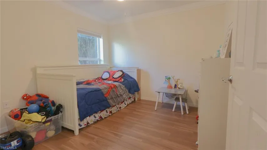 Bedroom 3 featuring baseboards, wood finished floors, and crown molding