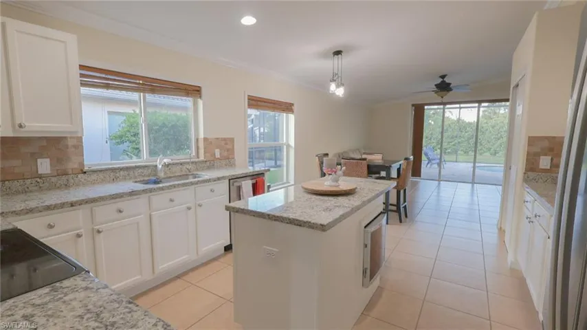 Kitchen with white cabinetry, tasteful backsplash, crown molding, a kitchen island, and a sink