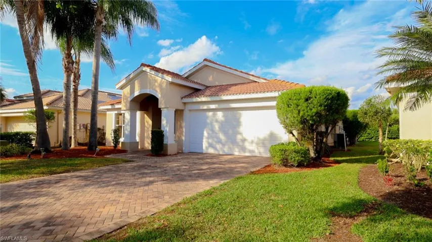 Mediterranean / spanish-style home featuring a tiled roof, decorative driveway, an attached garage, a front yard, and stucco siding