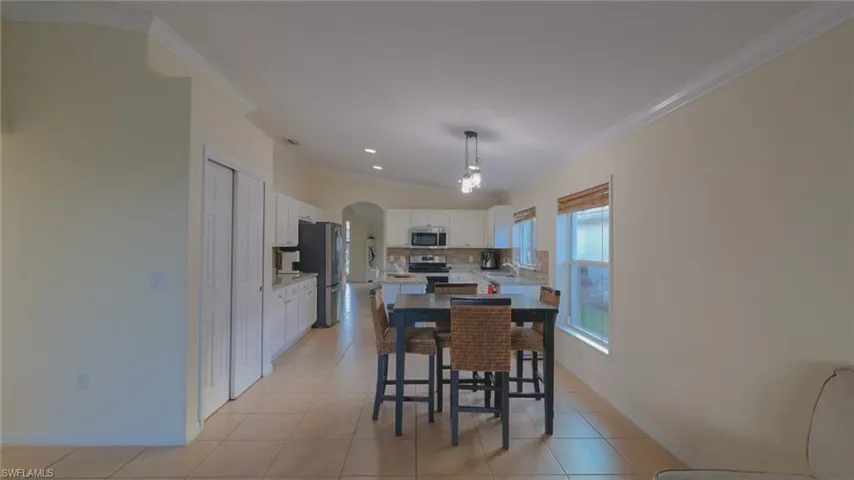 Dining area with light tile patterned flooring, ornamental molding, baseboards, and arched walkways