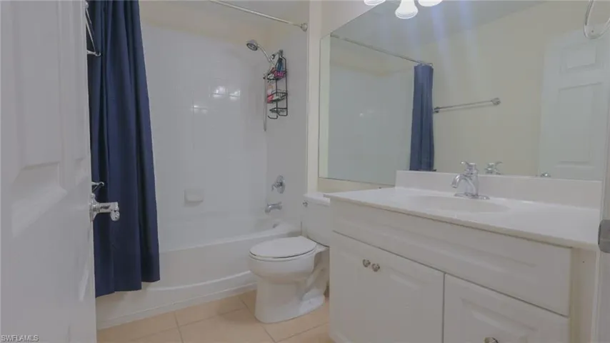 Full bathroom featuring shower / bathtub combination with curtain, tile patterned floors, toilet, and vanity