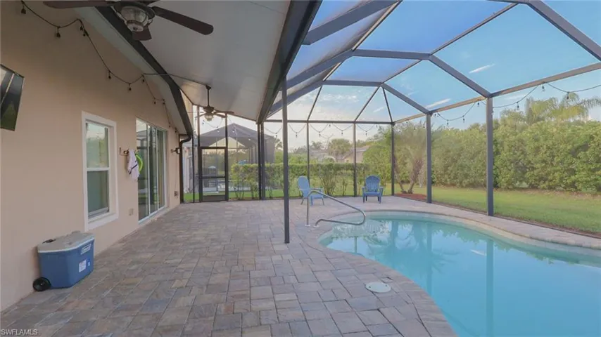 Outdoor pool with a ceiling fan, glass enclosure, and a patio area